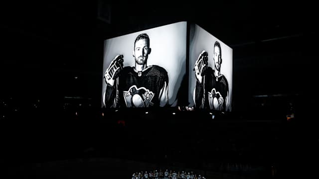Oct 30, 2023; Pittsburgh, Pennsylvania, USA; Members of the Anaheim Ducks and the Pittsburgh Penguins stand at center ice for a moment of silence at the PPG Paints Arena to honor former Penguin forward Adam Johnson (on scoreboard) who was tragically killed in a hockey related accident in Europe.